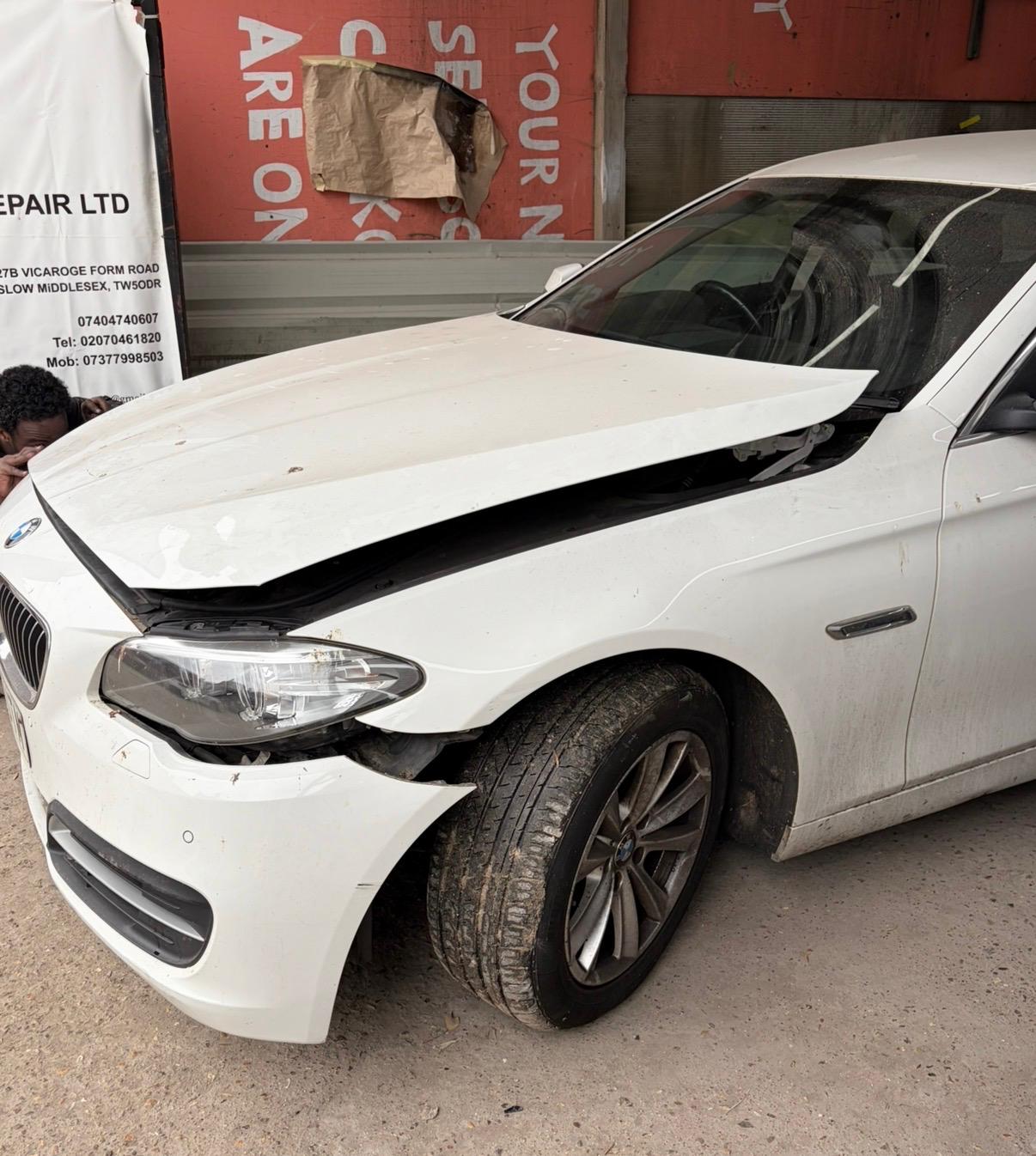 White BMW 5 Series with serious front-end damage before repair